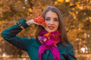 mooi jong meisje in een roze hoofddoek en hijs- arm houdt takje van lijsterbes detailopname foto