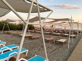 zon ligstoelen en zonnescherm met paraplu's Aan de strand Aan de zee Aan vakantie in een toerist warm oostelijk tropisch land zuidelijk toevlucht foto