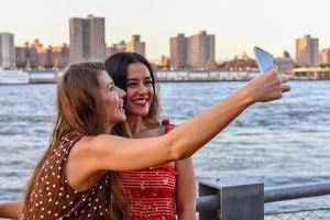 twee meisjes interactie met een mobiel telefoon en nemen dwaas selfie foto's in nieuw york stad foto