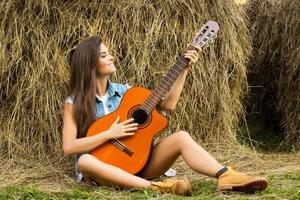 jong en gelukkig vrouw spelen gitaar in de dorp foto