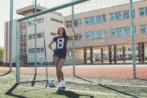 mooi meisje met bal Aan de voetbal veld- foto