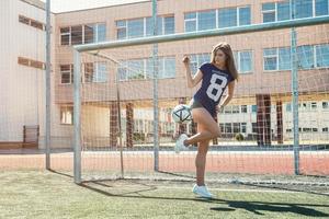 mooi meisje met bal Aan de voetbal veld- foto