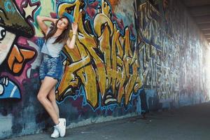 meisje in denim overall poseren tegen muur met graffiti foto