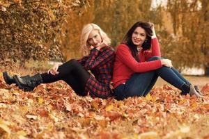 twee mooi meisjes vrienden hebben pret in herfst park foto