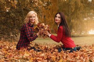 twee mooi meisjes vrienden hebben pret in herfst park foto