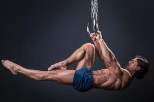 sterk en gespierd gymnast vent Aan de ringen foto