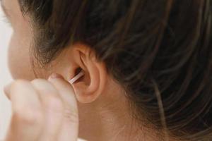 vrouw schoonmaak oor met een katoen wattenstaafje foto
