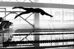 professioneel vrouw zwemmer jumping in naar de zwembad foto