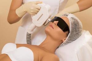 vrouw in professioneel schoonheid salon gedurende foto-epilatie procedure in kliniek foto