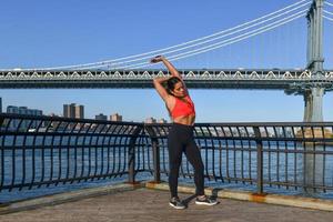 vrouw jogger uitrekken door de Manhattan brug in de Dombo Oppervlakte van Brooklyn in nieuw york stad foto