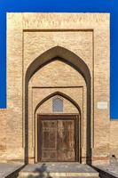 facade van de oude caravanserai ulugbek tamokifurus, 19e eeuw, met gesneden houten deur in bukhara, Oezbekistan. foto