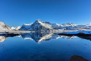boos door bo met bergen reflecterend in de water. in de lofoten eilanden, Noorwegen in de winter. foto
