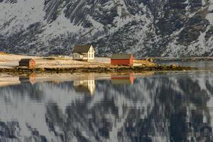 boos door bo met bergen reflecterend in de water. in de lofoten eilanden, Noorwegen in de winter. foto