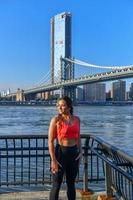 vrouw jogger uitrekken door de Manhattan brug in de Dombo Oppervlakte van Brooklyn in nieuw york stad foto