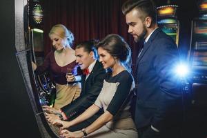 groep van vrienden spelen sleuf machines in casino foto