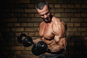 bodybuilder aan het doen opdrachten voor biceps met een halters foto