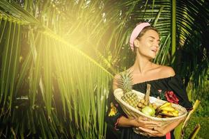 gelukkig jong vrouw met een mand vol van exotisch fruit foto