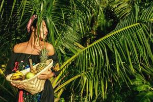 gelukkig jong vrouw met een mand vol van exotisch fruit foto