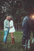 jong paar in omhelzing Aan de weide met een paarden foto