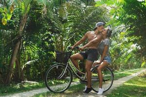 jong paar rijden een fiets door land weg in warm land foto