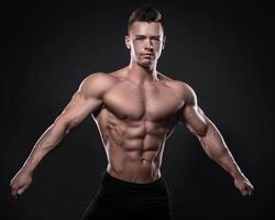 jong bodybuilder is tonen zijn spieren in studio foto