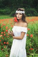 mooi vrouw in veld- met een veel van papaver bloemen foto