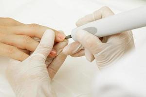 manicure meester werk. dichtbij omhoog van vrouw nagels en handen met een speciaal machine hulpmiddel. foto