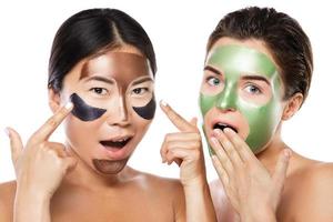 twee mooi meisjes met kleurrijk afpellen maskers Aan hun gezichten foto