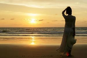 vrouw Aan de strand gedurende zonsondergang tijd foto