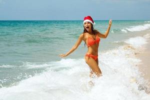 vrouw vervelend bikini en Kerstmis hoed Aan de strand. winter vakantie in de warm landen. foto