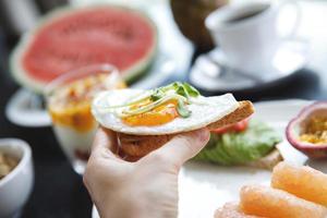 vrouw is aan het eten geroosterd brood met een gebakken ei. foto