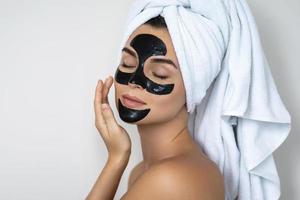 jong en mooi vrouw met zwart afpellen masker Aan haar gezicht foto
