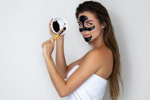 jong en mooi vrouw met zwart afpellen masker Aan haar gezicht foto