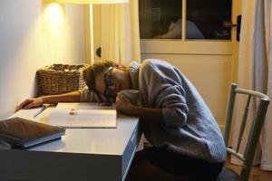 moe vrouw leerling is slapen Aan de bureau foto