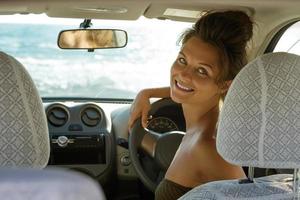 gelukkig vrouw bestuurder is zittend in de auto foto