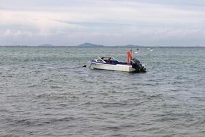 wit verf motor boot en blauw verf binnen met niemand binnen drijvend ergens Bij de zee. foto