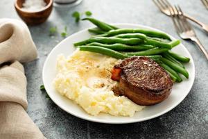 traditioneel avondeten maaltijd met een spek verpakt steak en aardappelen foto