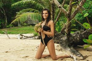 vrouw met een kokosnoot drinken Aan de tropisch strand foto