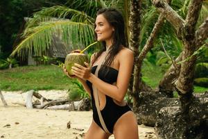 vrouw met een kokosnoot drinken Aan de tropisch strand foto