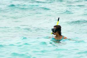 vrouw in de zee gedurende snorkelen in blauw water foto