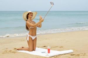 mooi vrouw is nemen selfie Aan de strand foto