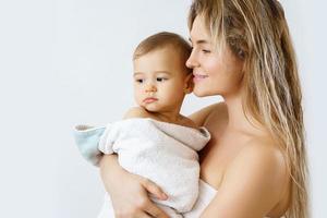 jong en gelukkig moeder en haar schattig weinig baby na het baden foto