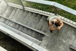 gespierd Mens is maken squats gedurende zijn straat training foto