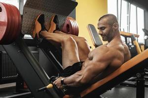 bodybuilder aan het doen een gezeten been druk op oefening in een Sportschool foto