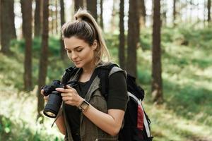 wandelaar gebruik makend van modern spiegelloos camera in groen Woud foto