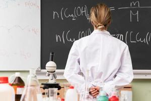 wetenschapper op zoek Bij chemisch vergelijking Aan een schoolbord gedurende een Onderzoek foto
