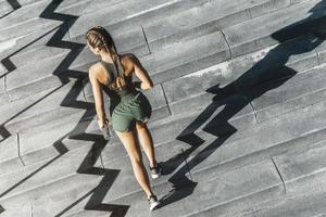 sportief vrouw is rennen boven door een beton trappenhuis foto