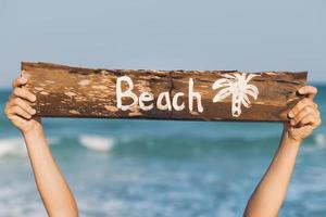 vrouw hand- en oud houten teken met belettering strand foto