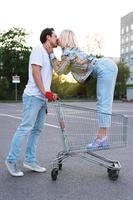 jong paar met een boodschappen doen trolley Aan supermarkt parkeren foto