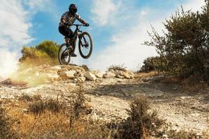 professioneel fiets rijder jumping gedurende bergafwaarts rijden Aan zijn fiets foto